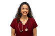 © PeopleVideos - Friendly female healthcare professional in burgundy scrubs, wearing stethoscope, beaming with confidence against clean white background