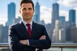 © Arif - Confident businessman standing on a stone walkway with a blurry city skyline behind him on a sunny day