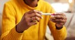 © peopleimages.com - Hands, pregnancy test and result with woman in living room of home for fertility or reproduction. Checking, ovulation and waiting with person closeup in apartment for family planning or ivf outcome