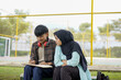 © Fajar - Collaborative Learning Two Students Sharing Notes Outdoors on a Bench, Focused on Studies and Academic Success
