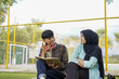 © Fajar - Young Couple Studying Together Outdoors, Engaging in Lively Discussion and Sharing Knowledge