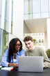 © Daniel - University students collaborating on project using laptop outdoors