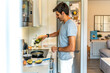© unai - Young man pouring olive oil into frying pan in modern kitchen