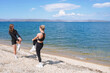 © Sergey - Two women stretch by the peaceful beach on a sunny day near clear blue water