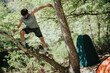 © qunica.com - Outdoor activity depicting a man climbing a tree at a scenic campsite surrounded by greenery.
