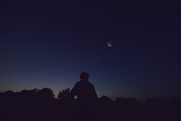 Wall Mural - Silhouette of a man observing Moon, Milky Way stars, planets and other celestial objects from a dark countryside location.