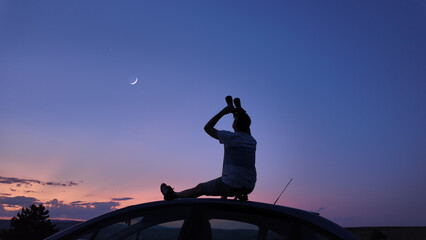 Wall Mural - Man watching stars, Milky Way, planets, Moon and other celestial objects from a car rooftop from a dark countryside location.