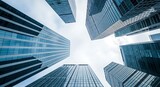 Looking up at a cluster of modern skyscrapers with glass facades reflecting the sky, showcasing urban architecture and progress