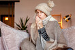 © Tatyana Gladskih - Woman warmly clothed and hat in a cold home sitting on couch