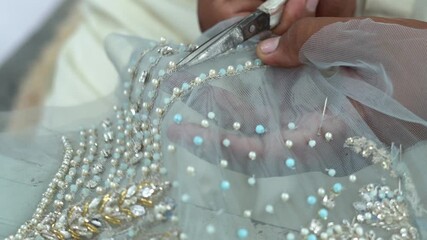 Wall Mural - Close Up Shot Of A Dressmaker Cutting Textiles During Beading Process In A Clothing Plant In Pakistan.