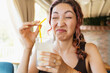 © EdNurg - Young woman making a disgusted funny face while drinking a glass of sour lemonade with a straw in a restaurant