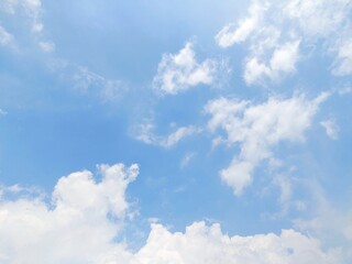 Wall Mural - Clear blue sky with light scattered white clouds on a bright sunny day in summer. Peaceful and serene clear blue sky background.