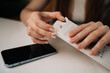 © dikushin - Close-up hands of happy woman with manicured nails carefully opening white retail package containing new phone adapter cable, ready to connect and charge. Concept of smartphone unboxing process.