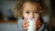 © The Little Hut - Charming Little Girl with Curly Hair Enjoying a Refreshing Glass of Milk, Promoting Health and Wellbeing