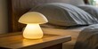 © RisanRisan - Close Up of Mushroom Shaped Night Lamp with Soft Yellow Dim Light on Bedside Table for Interior Concept