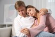 © New Africa - Worried couple with pregnancy test on sofa at home