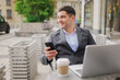 © muse studio - Man in suit works at outdoor cafe with phone and laptop