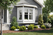 © heerim studio - Stylish gray home exterior with bay window and landscaping offers charm and curb appeal.