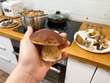 © irinad85 - A man prepares mushrooms in the kitchen. He holds a mushroom in his hand against the background of the kitchen.