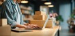 © SKIMP Art - close-up of a woman working on a laptop at a wooden desk in a modern office she is wearing casual and standing near a store counter with boxes nearby Generative AI