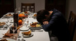 © Pink Zebra - Thanksgiving loneliness and mental health awareness concept wide banner, adult man resting head on hands at festive dinner table with autumn decor