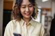 © Jovo Jovanovic/Stocksy - Smiling woman with curly hair looks at her phone.