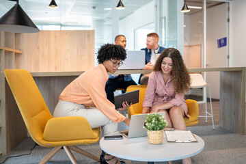 Businesswomen collaborating on project in modern office using laptop