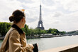 © Adrian Rodd/Stocksy - A female tourist admiring the Eiffel Tower from the Seine River