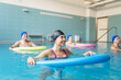 © Santi Nuñez/Stocksy - Senior patients doing water aerobics with pool noodles