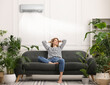 © New Africa - Woman relaxing on sofa surrounded by potted houseplants at home. Air conditioner keeping comfortable temperature in room