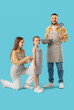© Pixel-Shot - Happy family in aprons with kitchen utensils on blue background
