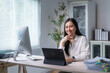 © Apichat - Asian businesswoman smiling and working with tablet and computer in modern office
