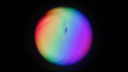 Wall Mural - A seamlessly looping video displays an iridescent rainbow circular flare gently distorting and rippling, forming a vibrant abstract optical illusion aura, spectrum, concentric