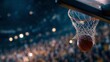 © SUYATI - A close-up shot of a basketball passing through the net. The background is a blurred stadium crowd with spotlights, capturing the moment of a successful score.