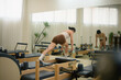 © saltdium - An Asian woman performing dumbbell row on Pilates reformer, building strength, posture, and core stability