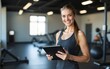 © ning - A happy female coach is standing in a gym with tablet in hands. High quality