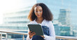 © peopleimages.com - Business woman, tablet and reading outdoor with analysis, review or research for economic report in city. Technology, female economist on balcony and digital information with survey for fiscal policy