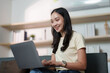 © itchaznong - Remote Work. Young woman smiling while using laptop at home.