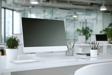 blurred background of a modern office interior with a white desk and computer monitor mockup, a minimalist work space for a graphic designer or web developer, with copy space.