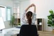 © itchaznong - Workplace Comfort. Young woman stretching in office chair to relieve tension and promote well-being.
