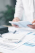© doidam10 - A businesswoman writes notes on clipboard while holding notebook at office desk with documents. Concept of business planning, accounting, financial management, productivity and corporate strategy.