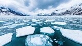 Panoramic view of ice floes floating on turquoise water with snowy mountains in the background, creating a breathtaking arctic landscape
