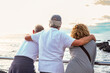 © luciano - Back view of group of senior friends enjoying a scenic ocean view together leaning on a seaside railing. Three adults embodying themes of friendship, active retirement, and coastal lifestyle