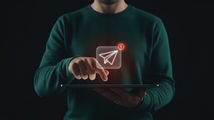 A man tapping on a tablet with glowing paper plane icon in dark scene, showing notification alert and digital communication