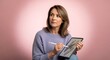 © Iis - A creative woman in a purple sweater uses a stylus to draw a detailed design on a tablet against a pink background.