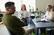© Mediaphotos - Man sitting with arms crossed facing away from two middle aged women, one gesturing while other taking notes during psychological counseling session