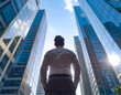© theshooter - Joven empresario de espaldas mirando al horizonte en la ciudad moderna en plano contrapicado representando éxito profesional emprendimiento liderazgo visión de futuro motivación y crecimiento laboral