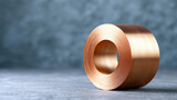 Copper wire cable coil with shiny metallic texture placed on gray surface with blurred background for industrial use