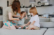 © SHOTPRIME STUDIO - Caring woman playing with her children in a cozy living room, nurturing family bond and joyful interaction, perfect for depicting daily family life.