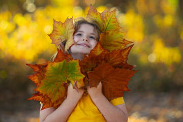 Wall Mural - Autumn kids Portrait In Fall Yellow Leaves. Little Child In Beautiful Autumn Park Outdoor. Kids play in autumn park. Children hold yellow leaves. Child boy with oak and maple leaf. Fall foliage.